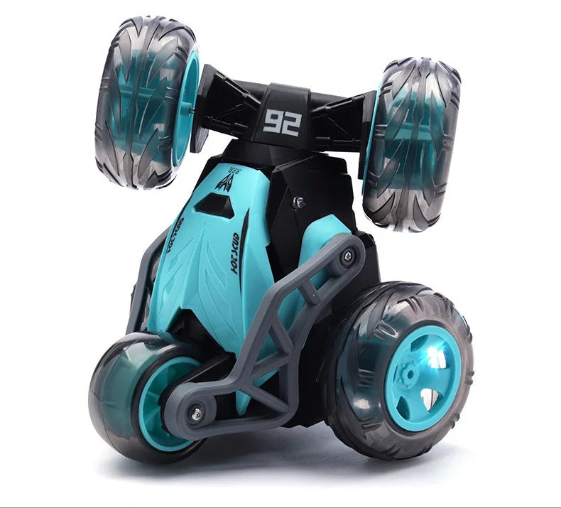 A black and teal stunt car with large wheels is shown against a white background.