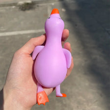 A hand holds a purple jumbo squishy duck stress ball fidget toy with orange accents.