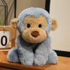 A light blue plush monkey soft toy with brown accents sitting on a wooden surface.