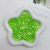 A white heart-shaped container filled with bright green acrylic ice strips for nail art and DIY crafts.