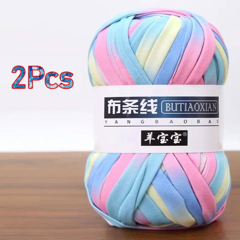 A skein of multi-colored soft chunky yarn, featuring stripes of pink, blue, and yellow, packaged for crochet and knitting.
