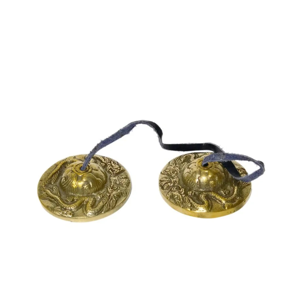 Handcrafted brass tingsha cymbals with eight auspicious symbols attached to dark cord