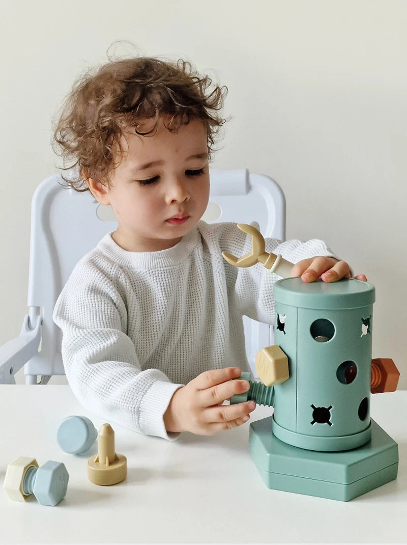 A toddler is using a green Montessori screwdriver board toy to practice fine motor skills and shape matching.