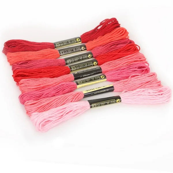 A set of multicolor embroidery floss skeins in shades of red, pink, and orange with a glitter finish.