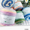 A variety of colorful gradient yarn balls in various shades of blue, pink, green, and yellow are displayed in a white crate.