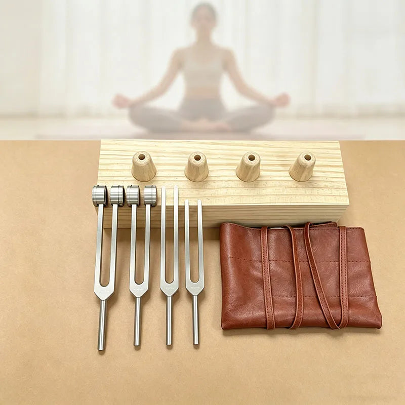 A set of silver tuning forks and wooden resonance boxes displayed on a light brown surface.