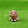 A small, light brown resin figurine of a hippo in a sitting pose on green grass.