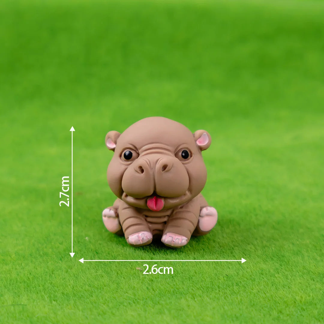 A small, light brown resin figurine of a hippo in a sitting pose on green grass.