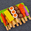 A tray of mini barbecue food items including sausages, eggs, and vegetables on a green plate.