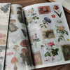 A close-up of a retro botanical sticker book featuring watercolor illustrations of flowers and plants on aged paper.