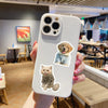 A hand holds a white phone case featuring stickers of a dog and a cat.