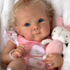 A close-up photo of a lifelike reborn baby doll with hand-rooted hair, featuring blue eyes and pink clothing.