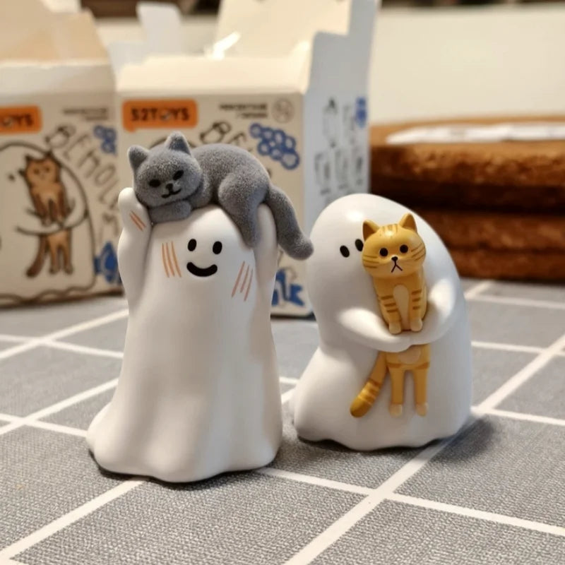 A white figurine of a cat is nestled inside, with another small orange cat figurine sitting beside it.