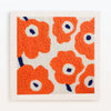 A square piece of white fabric with an orange flower pattern embroidered in orange yarn and blue accents.