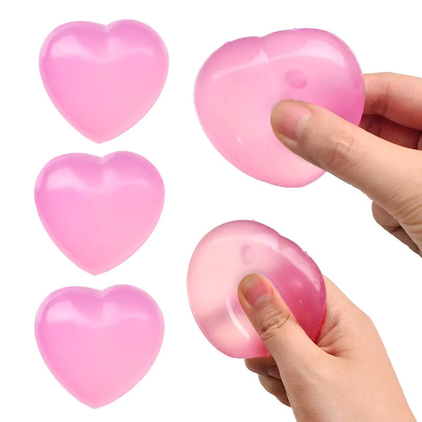 Pink silicone heart-shaped stress relief balls being held by a hand