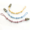 Three silicone pacifier clips in yellow, blue, and pink with attached strings.