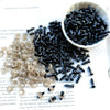 A bowl of black plastic safety eyes next to a pile of clear plastic safety eyes for crafting.