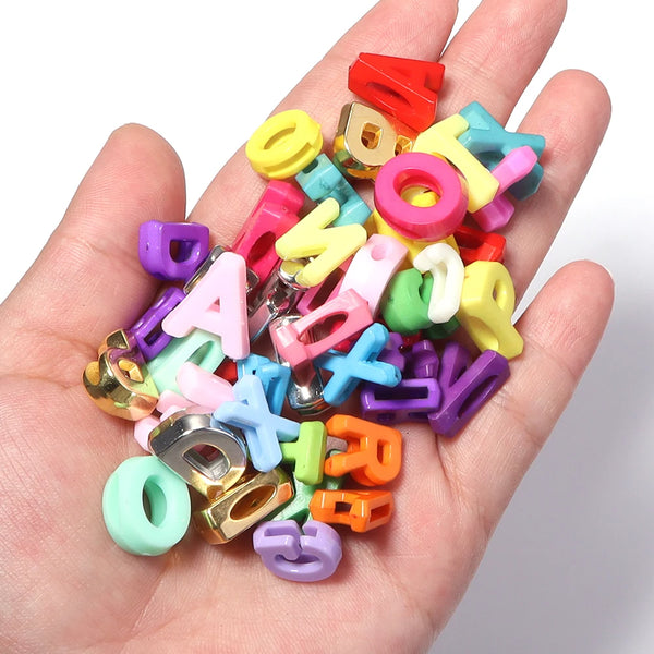A hand holds a collection of colorful mixed acrylic letter beads for DIY crafts.