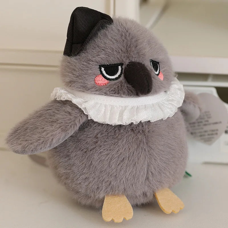 A gray cartoon bird plush with black eyes and a white ruffled collar sits on a white surface.