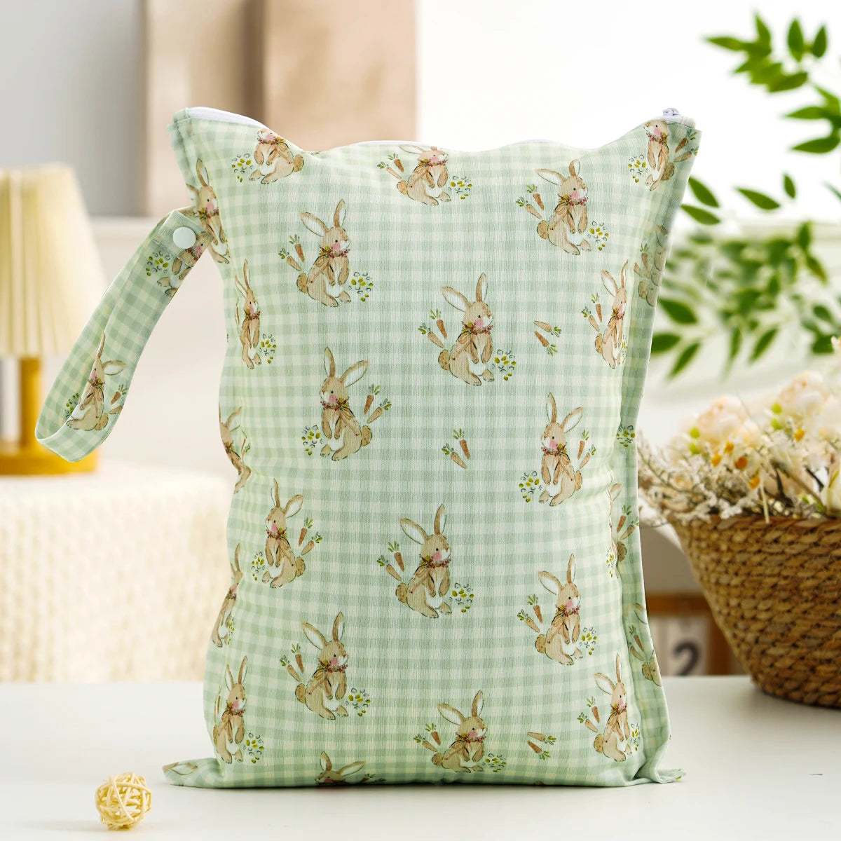 A light green patterned reusable zippered diaper cover and wet bag with rabbit illustrations.
