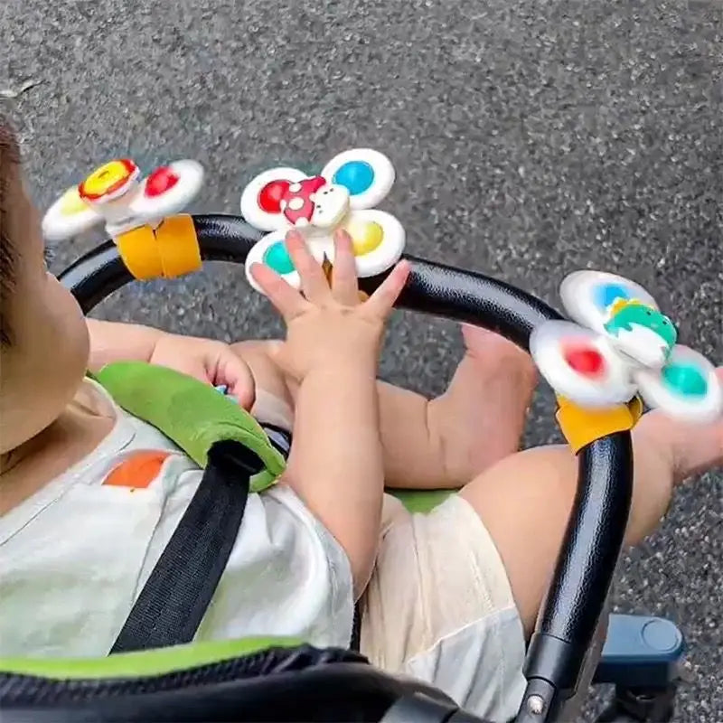 A toddler is playing with a spinning suction cup bath toy featuring colorful flowers and rings.