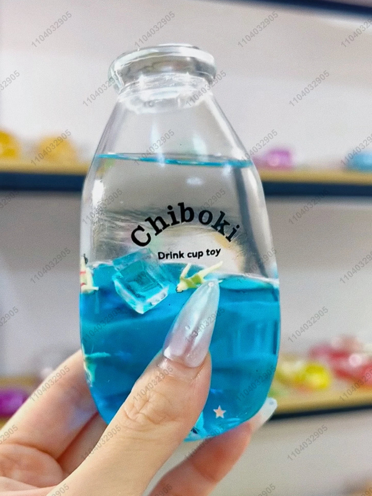 A hand holds a clear bottle labeled Chiboki, which contains blue liquid and ice cubes, used as a drink cup toy.