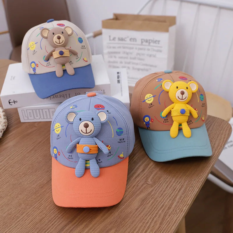 A set of three toddler bear baseball caps in various colors, including blue, orange, and pink.