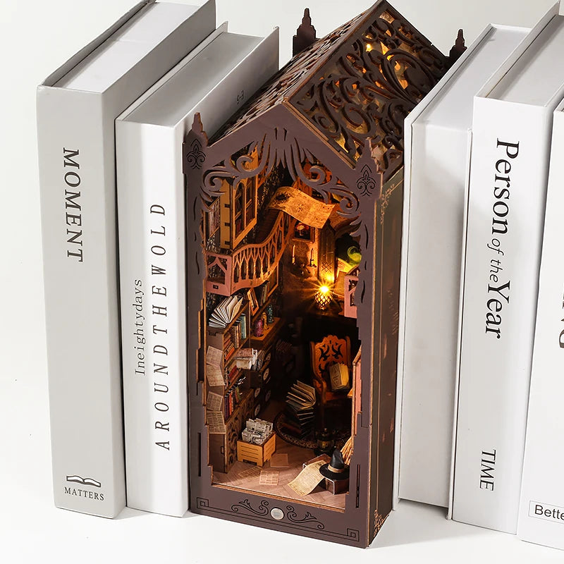 A DIY book nook kit featuring miniature furniture and a detailed diorama inside a wooden house structure.