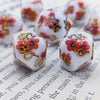 A set of milk white resin dice featuring a black kitten design with red floral accents.