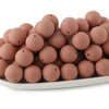 A pile of round, matte pink silicone beads for jewelry making and DIY crafts.
