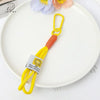 Yellow soft bunny plush keychain with an orange cord and bow charm resting on a white plate.