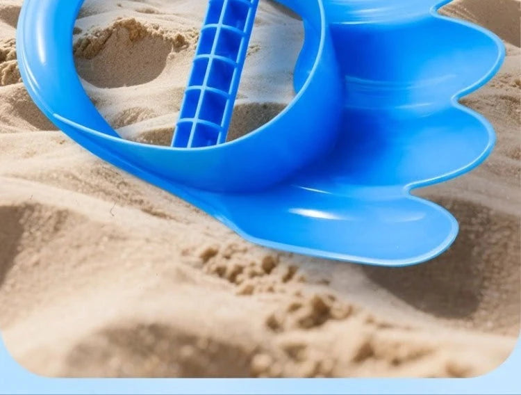 A bright blue dinosaur claw sand digging toy is shown scooping sand in a sandy environment.