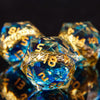 A close-up of a set of resin dice with golden elven numbers, illuminated against a dark background.