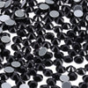 A close-up view of small, round black glass crystal hot fix rhinestones scattered on a white background.