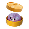 A yellow plastic container holds a purple glitter dumpling squishy stress relief toy.