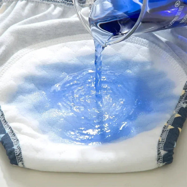 A hand pours blue liquid onto a white cloth, creating a swirling blue pattern on the fabric.