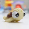 A cute, yellow rubber baby toy with large eyes and a brown detail is shown on a white surface.