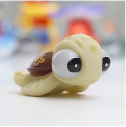 A cute, yellow rubber baby toy with large eyes and a brown detail is shown on a white surface.