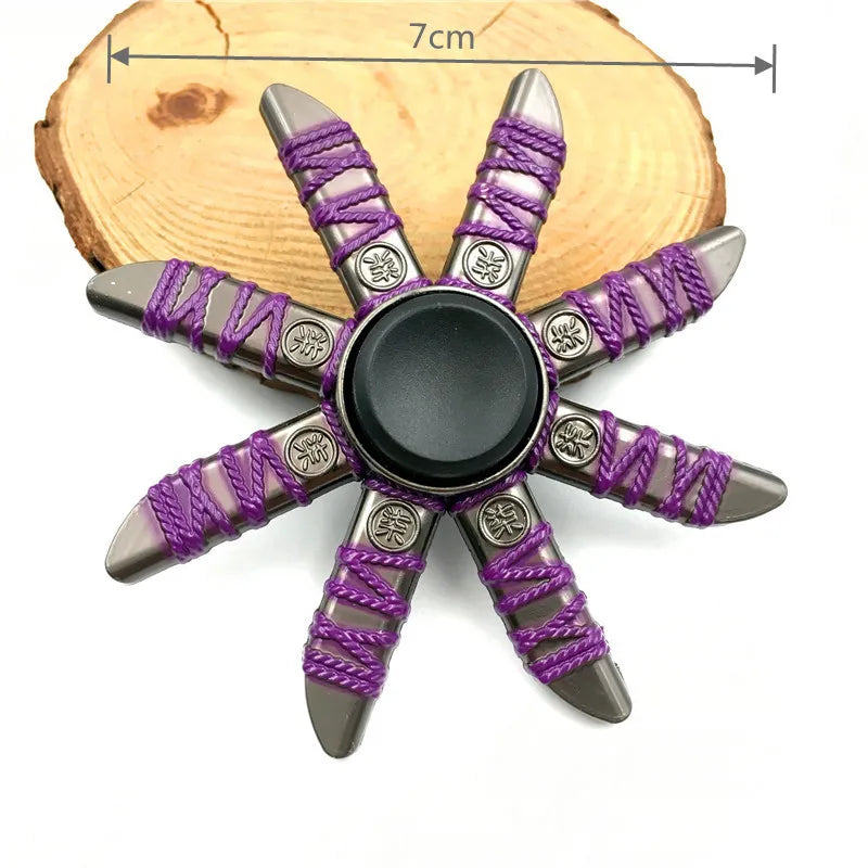 A metal fidget spinner with a star shape and purple braided string detail resting on a wooden surface.