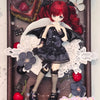 A highly detailed figure of a red-haired angel with black wings and gothic attire displayed in a wooden frame.