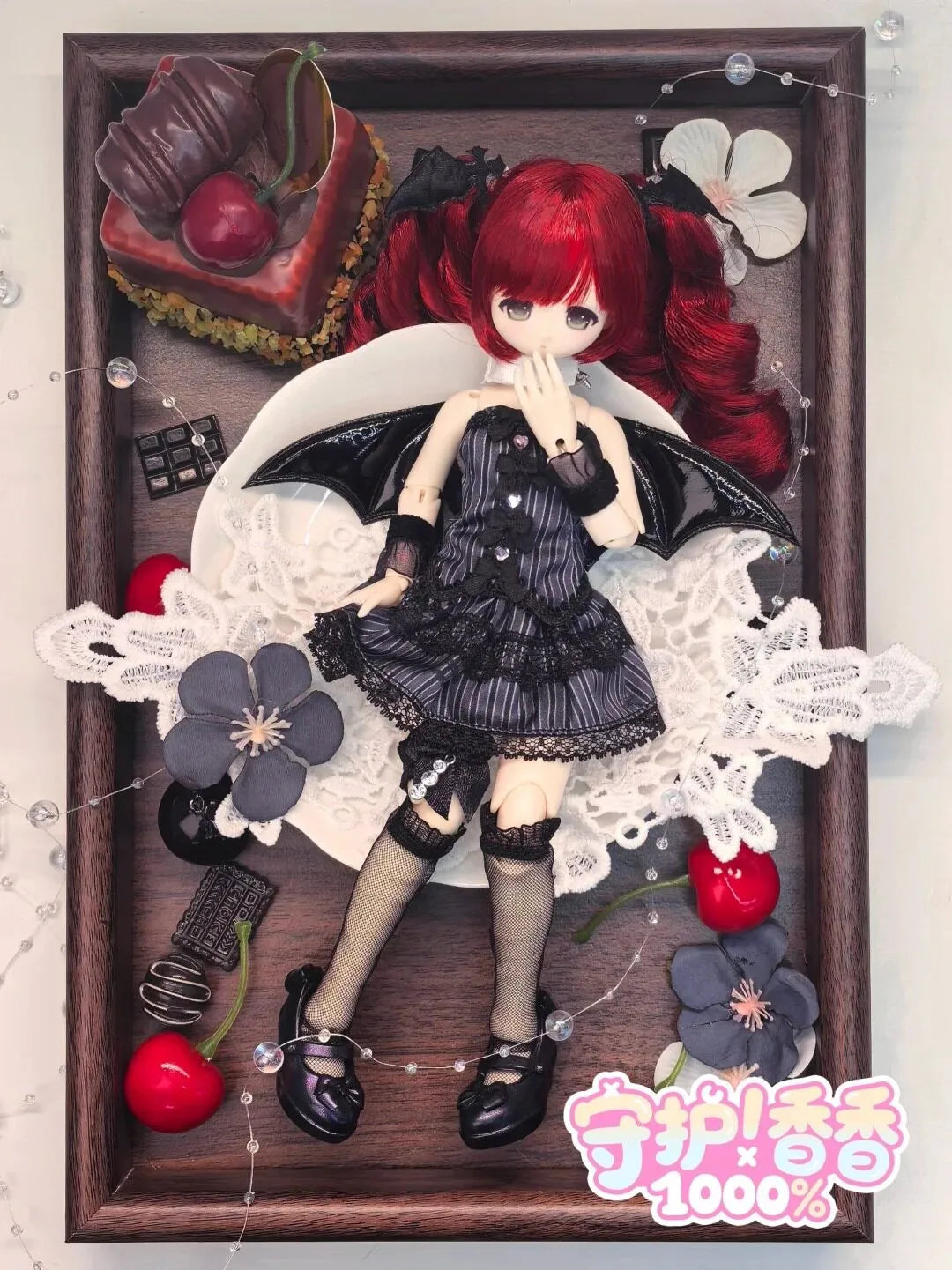A highly detailed figure of a red-haired angel with black wings and gothic attire displayed in a wooden frame.