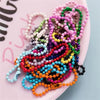 A colorful assortment of durable ball bead chains for DIY jewelry making displayed on a pink surface.