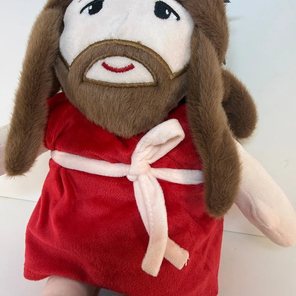 A plush doll depicting Jesus with long brown hair and a beard wearing a red robe.