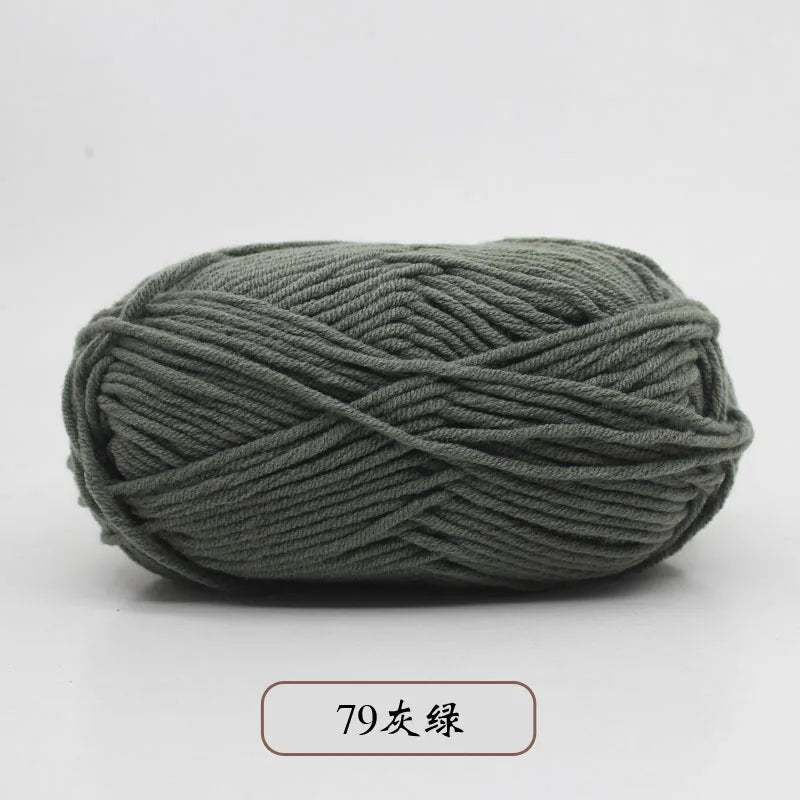 A ball of dark gray pre-dyed milk cotton yarn, 79 strands thick, shown lying on a white surface.