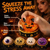 A hand squeezes an orange ghost-shaped squishy toy for stress relief alongside other Halloween-themed fidget toys.