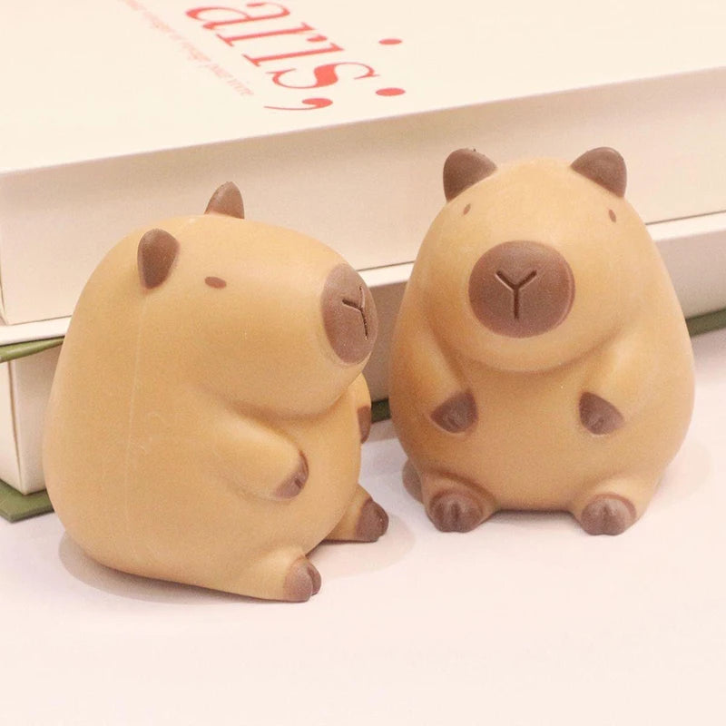 A pair of light brown capybara squeeze stress relief toys sitting on a white surface.