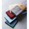 A stack of classic cotton-linen dinner napkins in various muted earth tones and blues.