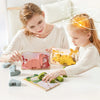 A mother and daughter are playing with a wooden animal threading and stacking toy set on a white table.