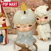 A collectible figurine of a pale, melting candle in a white ceramic holder with a small yellow top.