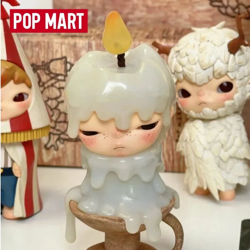 A collectible figurine of a pale, melting candle in a white ceramic holder with a small yellow top.